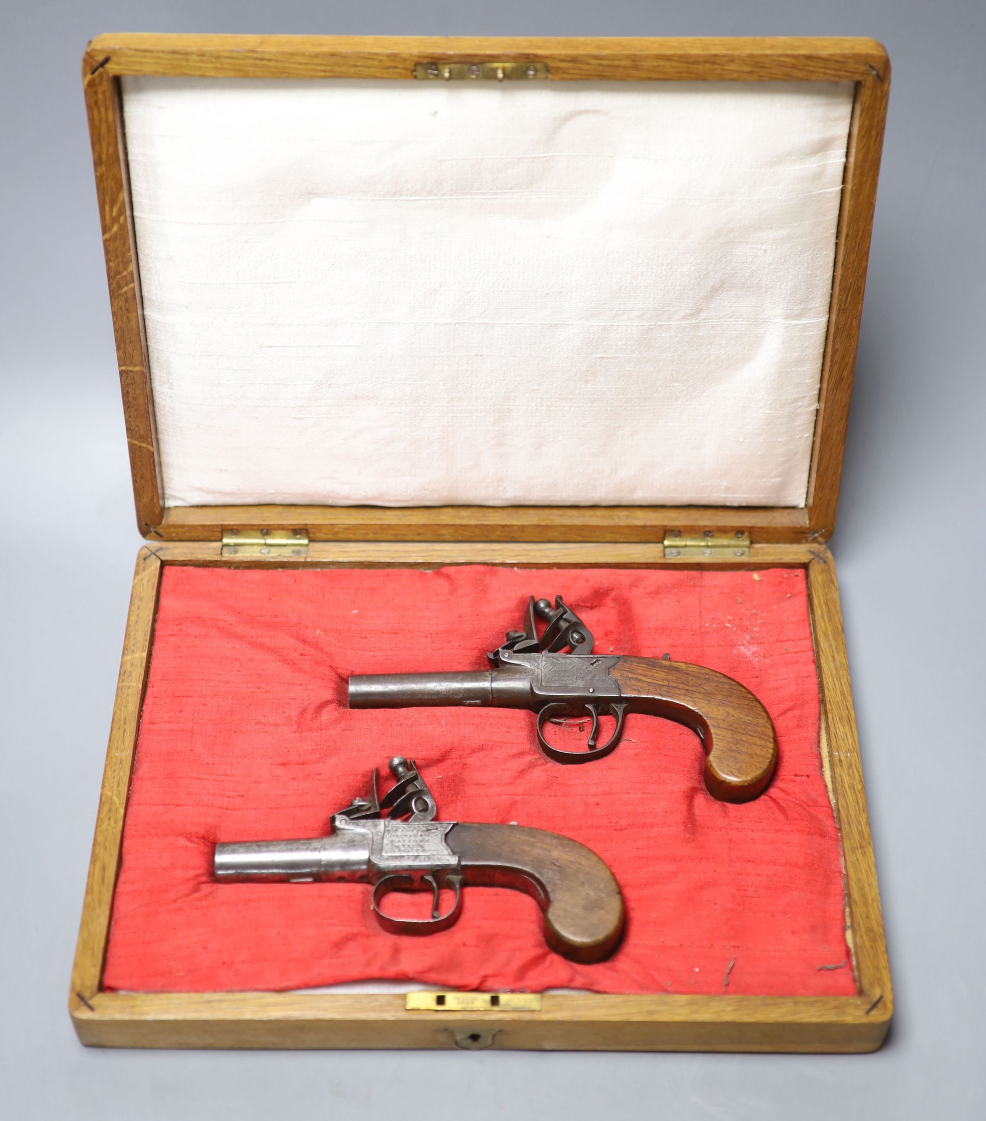 Two 19th century Dunderdale, Mabson & Labron steel flintlock pocket pistols, turn off barrels and walnut butts, in a later oak case